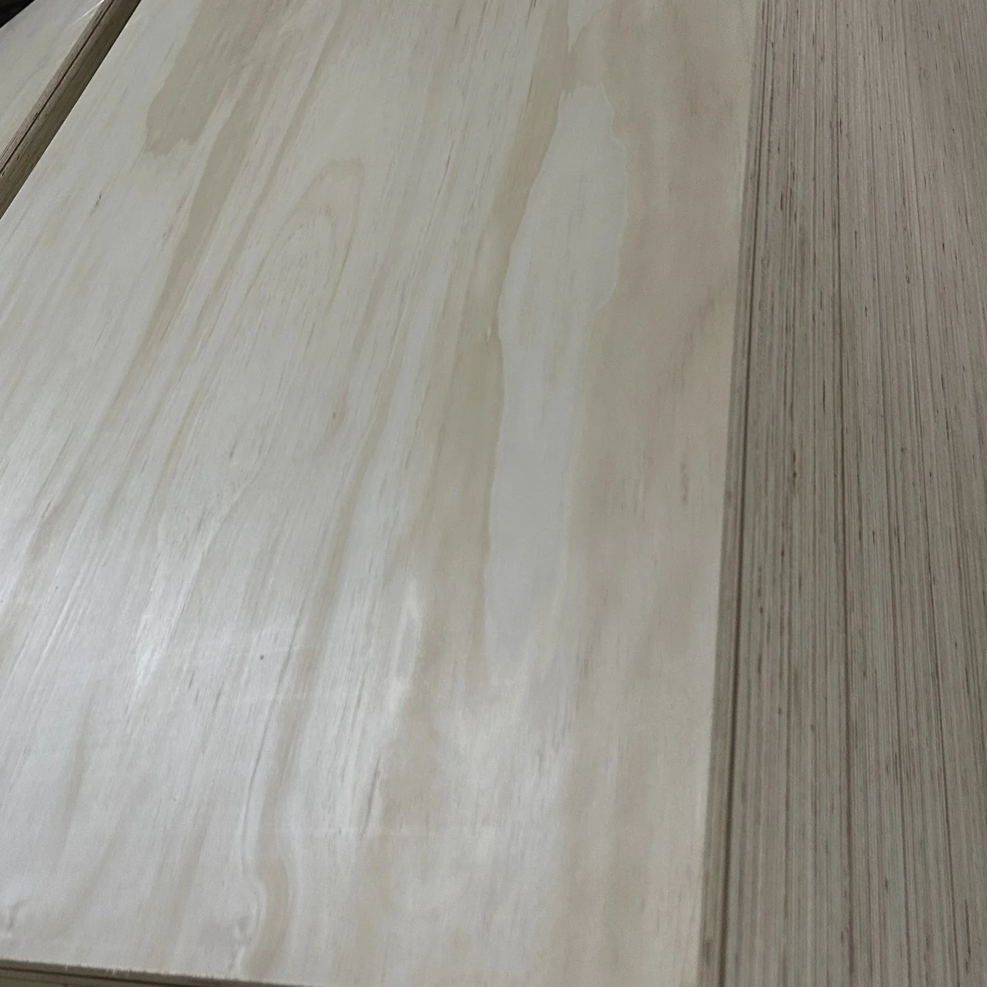 Pine-faced plywood sheet with pale cathedral grain and the layered sheet edge along the right